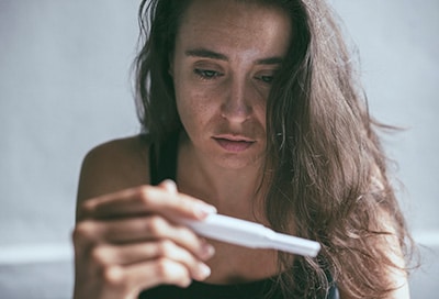 worried woman looking at pregnancy test